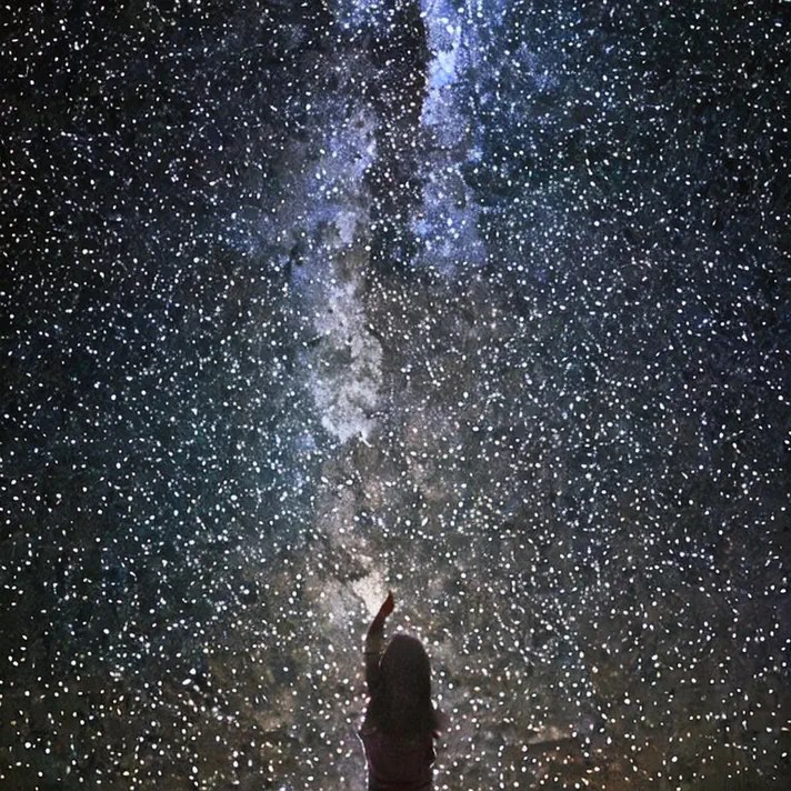 starred - a woman reaches up into the night sky to touch the stars